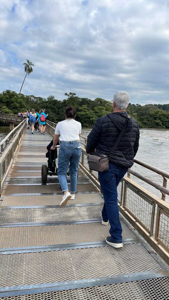 Na imagem, visitante com cadeiras de rodas percorrendo uma rampa que dá acesso a vista das Cataratas.